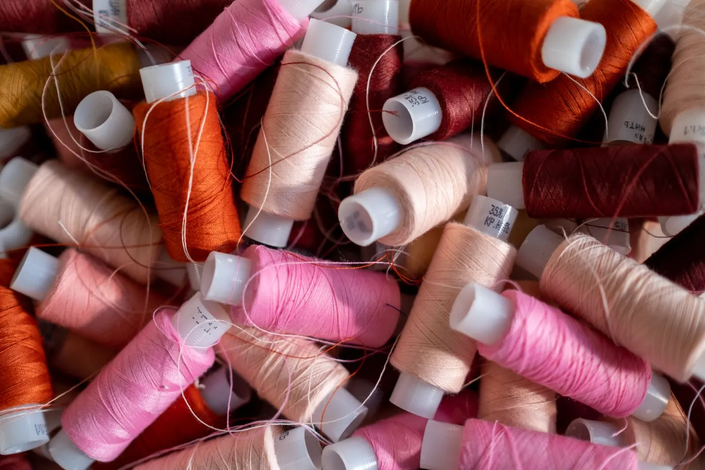 Bobines de fil à coudre roses, orangées et bordeaux
